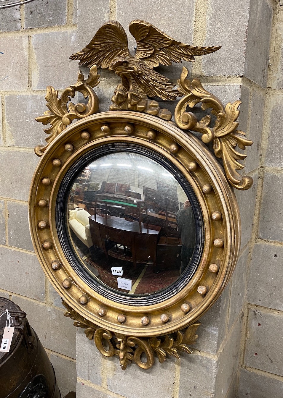 A Regency carved giltwood convex wall mirror with eagle pediment, width 59cm, height 92cm